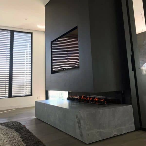 Modern double-sided gas fireplace with concrete base in a minimalist living room.