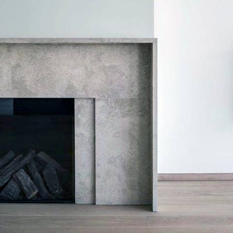 Minimalist concrete fireplace with sleek modern design and blackened logs.