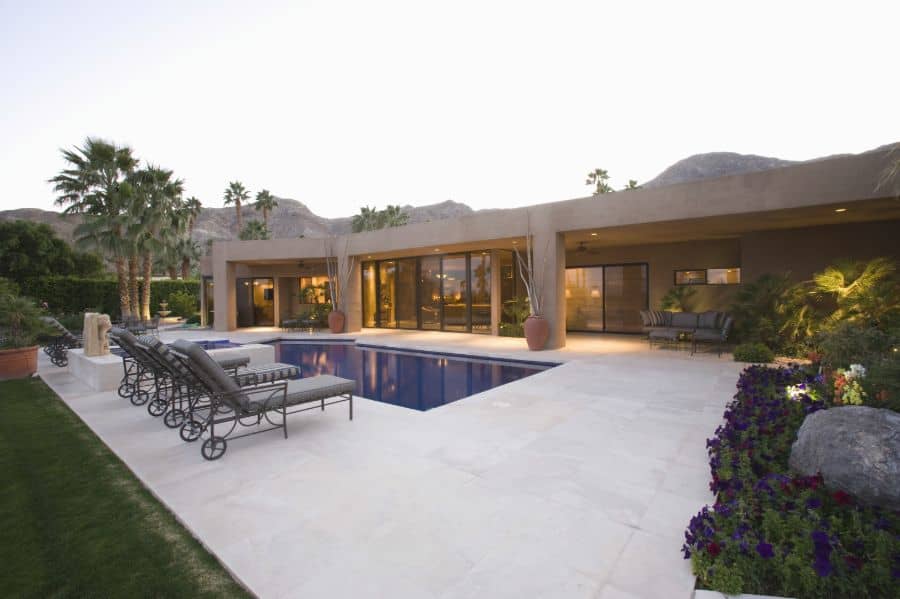 luxury home with concrete pool deck and sun loungers