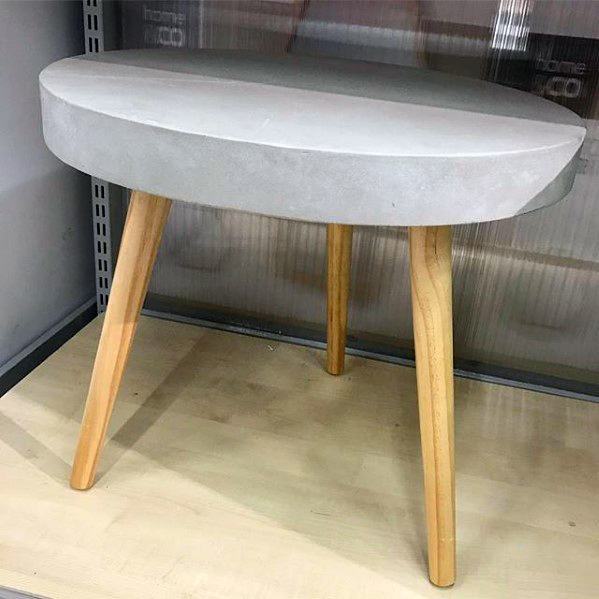 Small round table with a gray concrete top and three wooden legs
