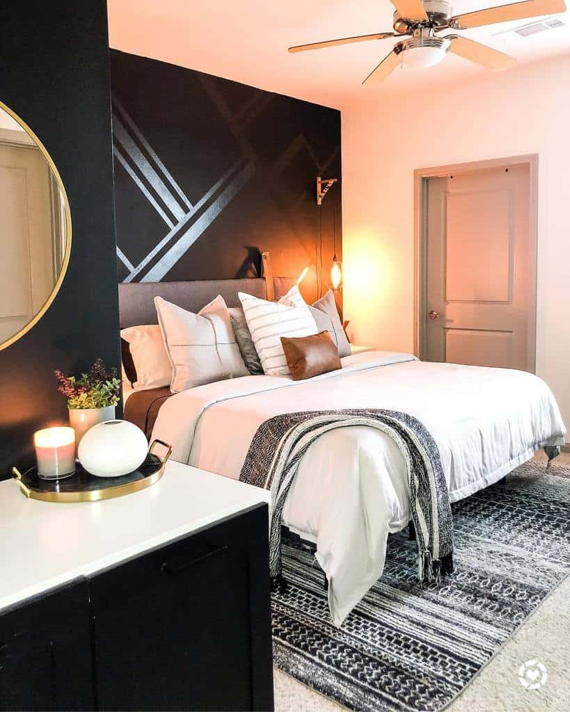 Modern bedroom with black accent wall, neutral bedding, ceiling fan, and geometric decor.