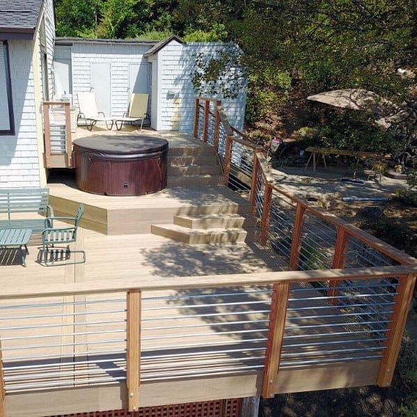 raised wood deck metal and wood railing hot tub green outdoor furniture