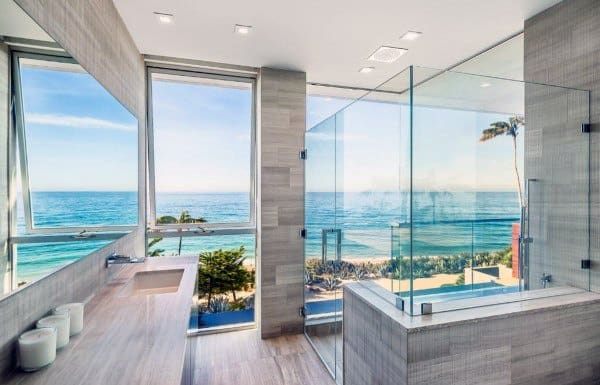 Modern bathroom with ocean view through large windows and glass shower enclosure