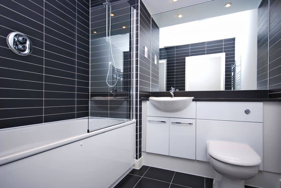 Contemporary black and white bathroom with bathtub, glass shower screen, and vanity.