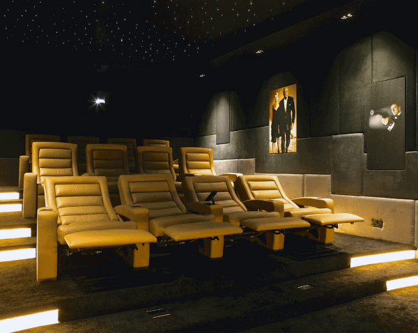 A luxurious home theater featuring yellow recliners, dim lighting, and a starry ceiling