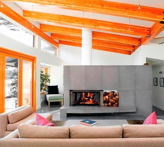 Contemporary concrete fireplace in a bright living room with wooden beams and cozy seating.