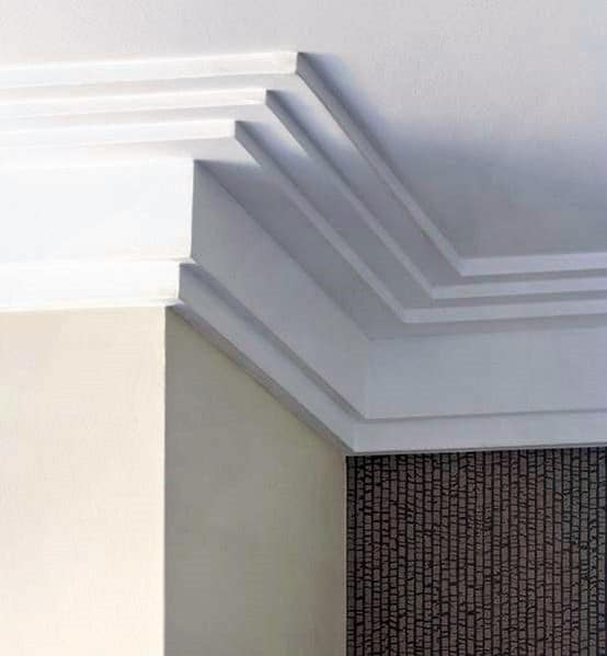 A sleek, contemporary room corner featuring clean, layered crown molding and a textured wall accent