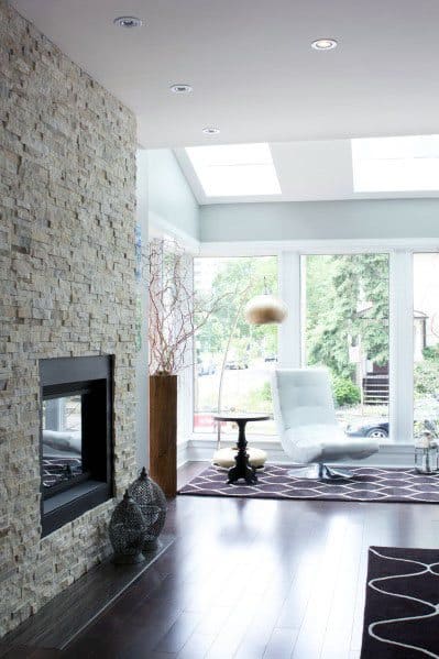 Contemporary stacked stone fireplace in a bright living space with skylights and modern furnishings