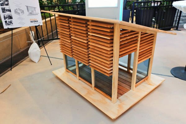 Model of a wooden doghouse with slanted roof and louvered walls