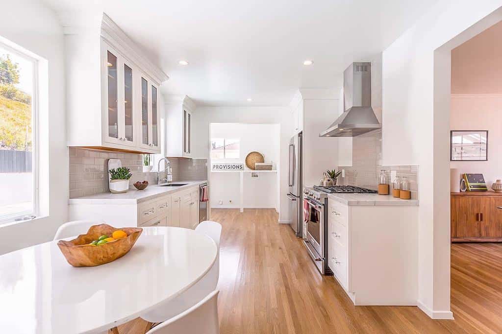 large open plan contemporary galley kitchen white cabinets dining room table fruit bowl