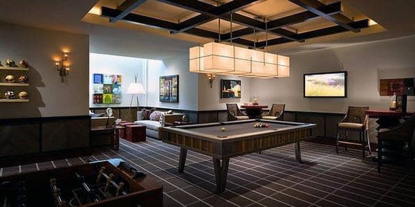 Chic game room with a pool table, cozy seating area, modern lighting, and wall art