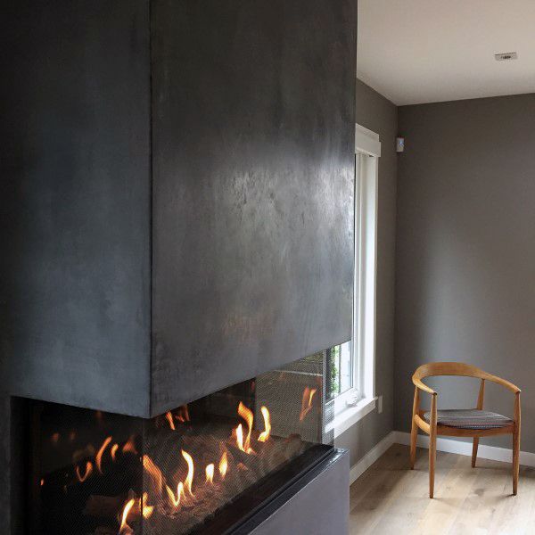 Modern corner gas fireplace with a dark concrete surround and glass panel detail.
