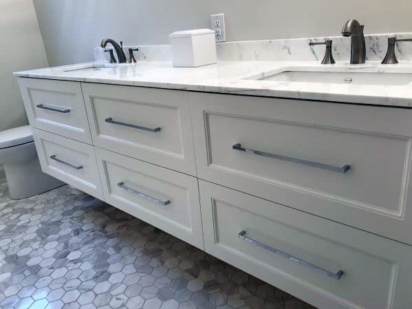 Contemporary white vanity with marble countertop, silver hardware, and hexagon tile floor.