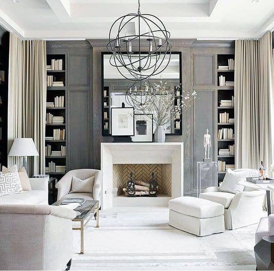 Elegant living room with a chandelier, fireplace, and plush seating by the bookshelf