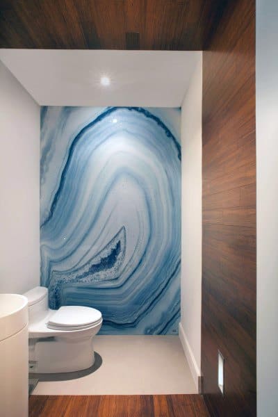 Modern half bath with a blue agate geode feature wall, white toilet, and wooden accents