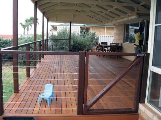 Wooden deck with railing, small blue stool, and outdoor seating by a welcoming gate