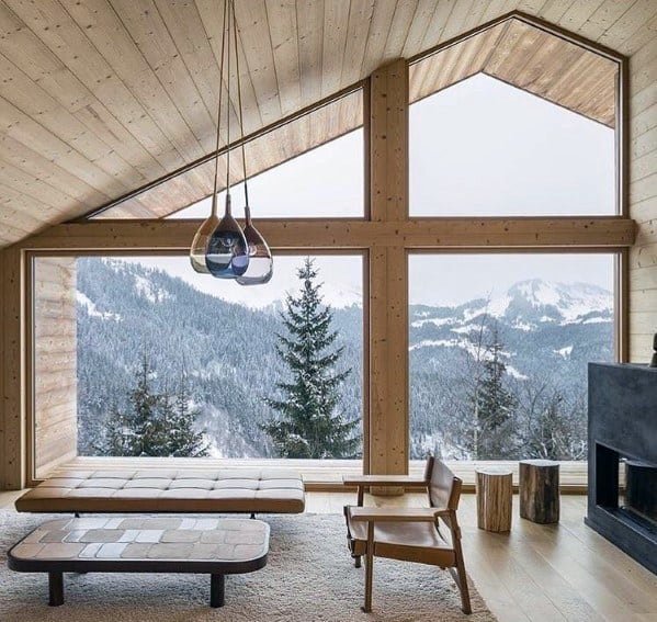Modern living room with wood ceiling, pendant lights, leather chair, bench seating, and fireplace.