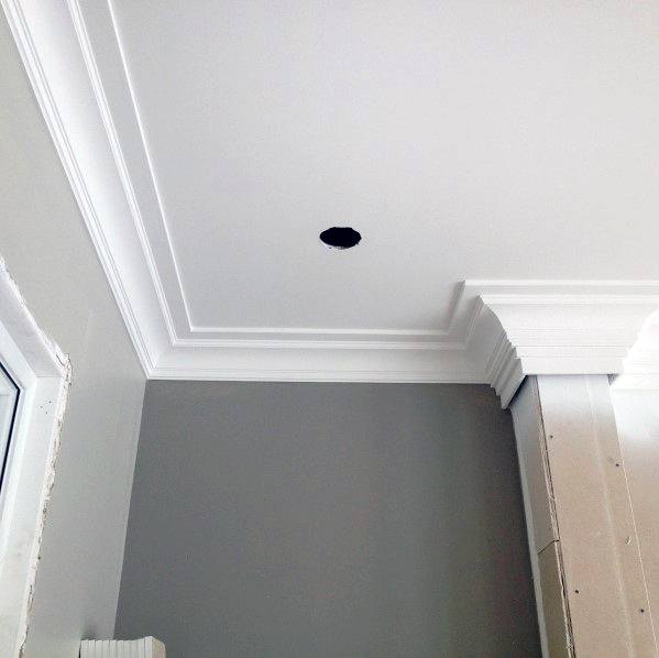 A modern room featuring crisp white crown molding, with a partially finished wall