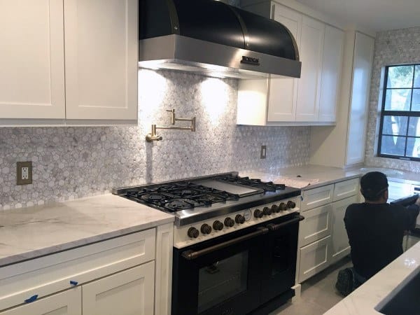 Sleek white backsplash with soft lighting complements the modern kitchen design.
