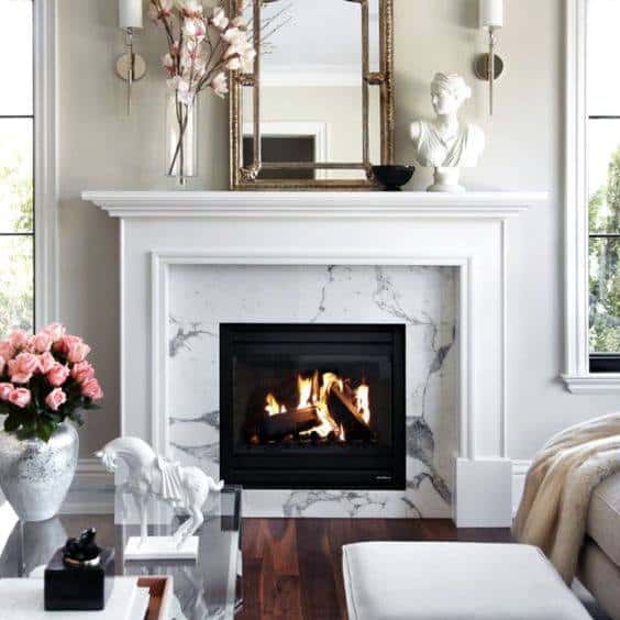 White marble fireplace with a classic mantel, gold mirror, and elegant decorative accents.