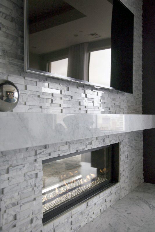 Contemporary fireplace with marble surround, stacked stone texture, and sleek modern mantel.
