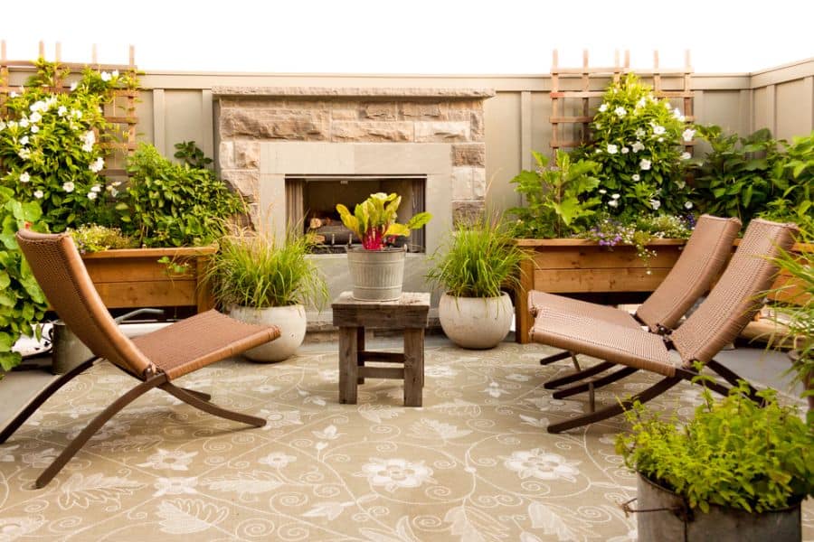 small backyard patio with pattern floor rug sun loungers and fireplace