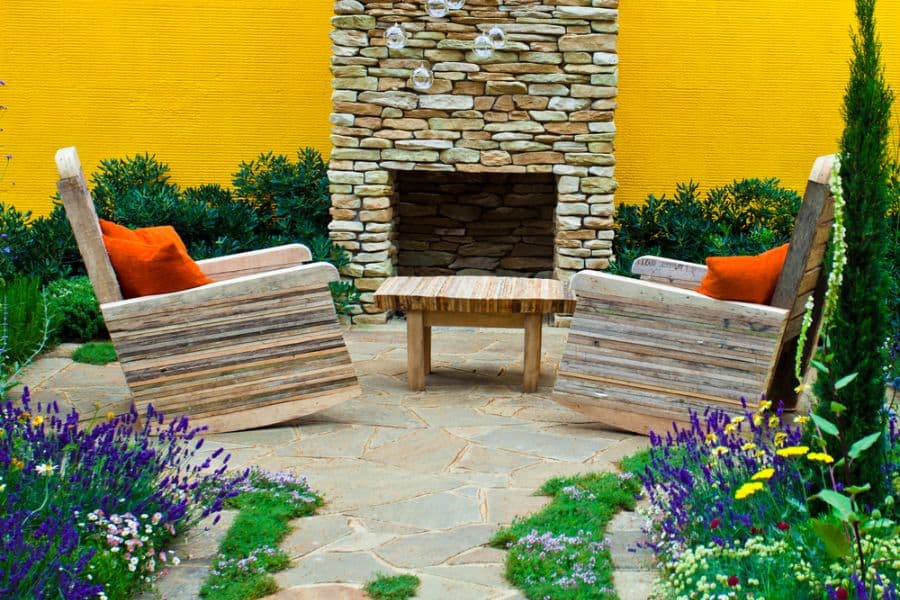 stone paver patio with wood armchairs and fireplace