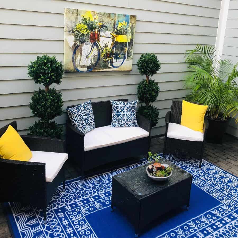 small modern patio with blue floor rug and black wicker furniture