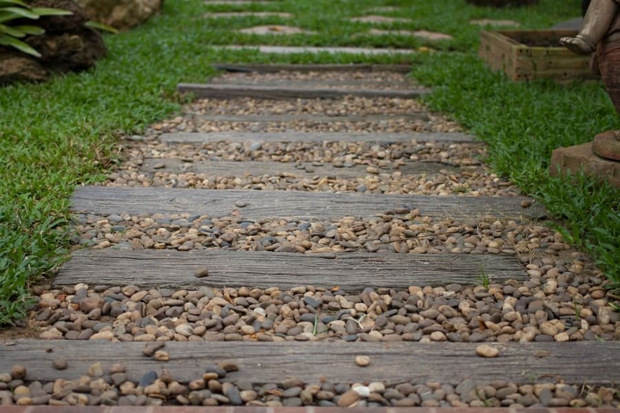 Walkway of stone and wood surrounded by green grass in a garden