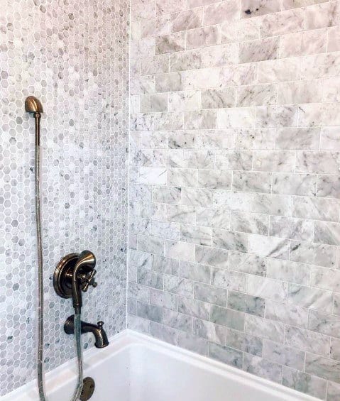 Bathtub with gray marble subway tile wall and small hexagon mosaic accent.