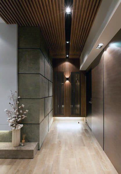 Modern hallway with slatted wood ceiling, textured walls, recessed lighting, and minimalist decor.