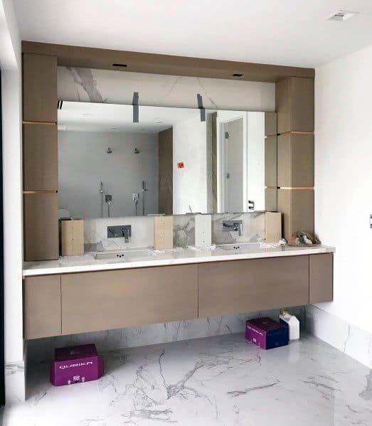 Contemporary wood bathroom vanity with large mirror, marble countertop, and built-in lighting.