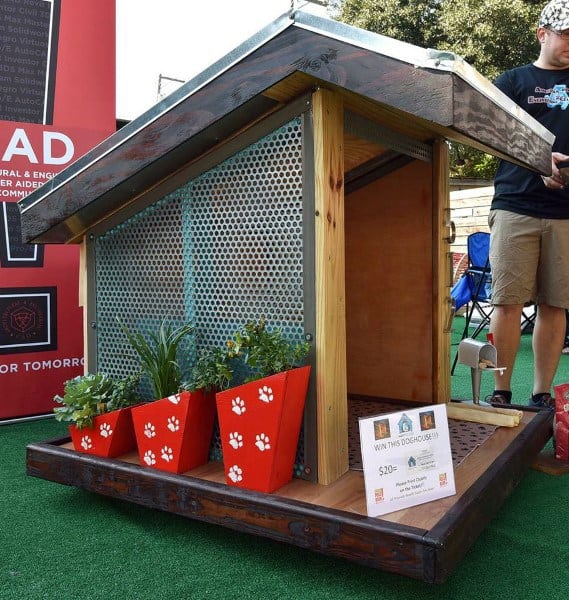 Contemporary dog house with metal mesh walls, a slanted roof, red paw print planters
