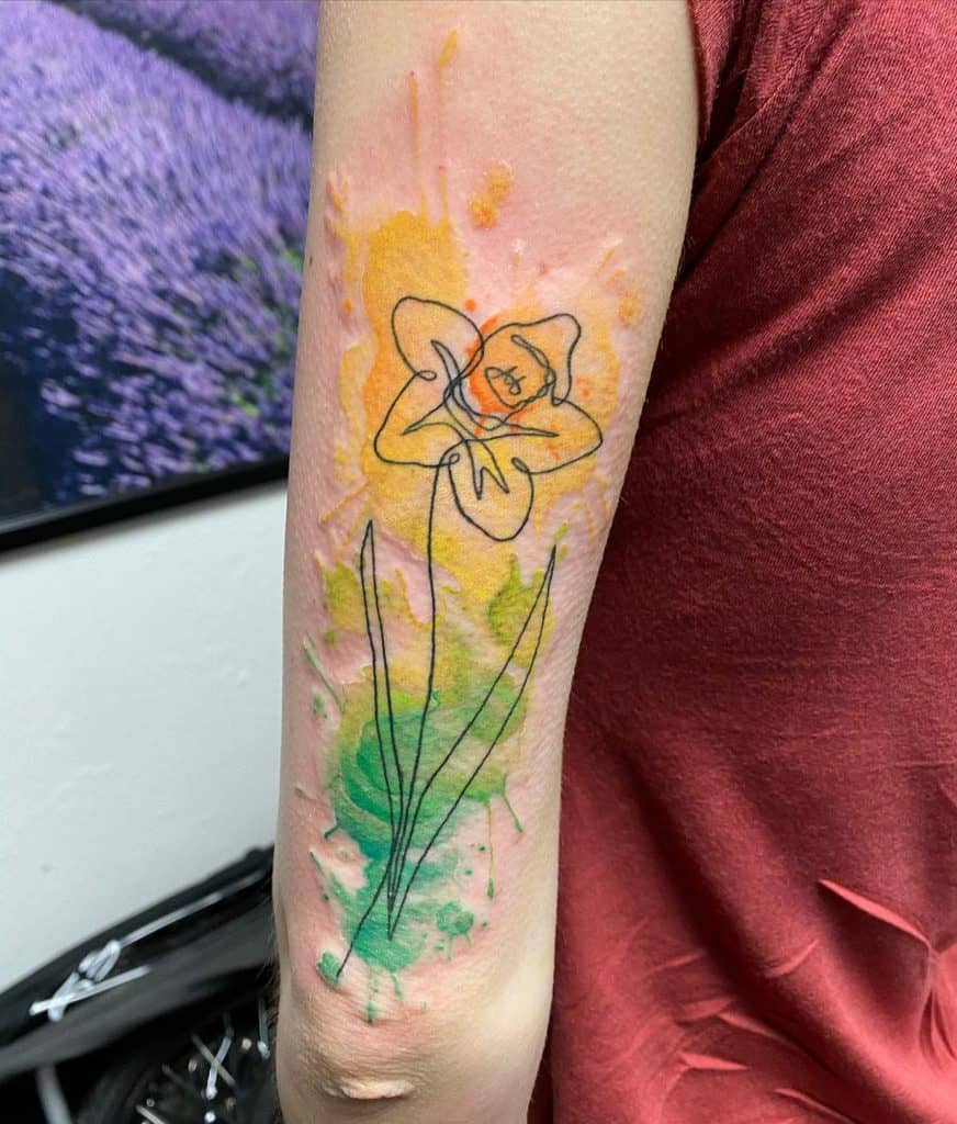 A vibrant, watercolor-style tattoo of a daffodil with bold black outlines, blending soft yellow and green hues.