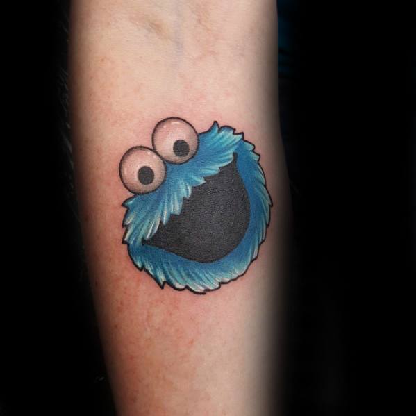 Minimalist Cookie Monster tattoo featuring his happy face with wide eyes and fluffy blue fur on a clean black background.
