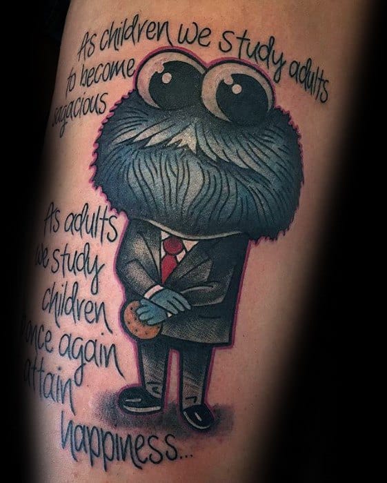 Cookie Monster tattoo in a suit holding a cookie, with thoughtful quote about childhood and happiness in stylized script.