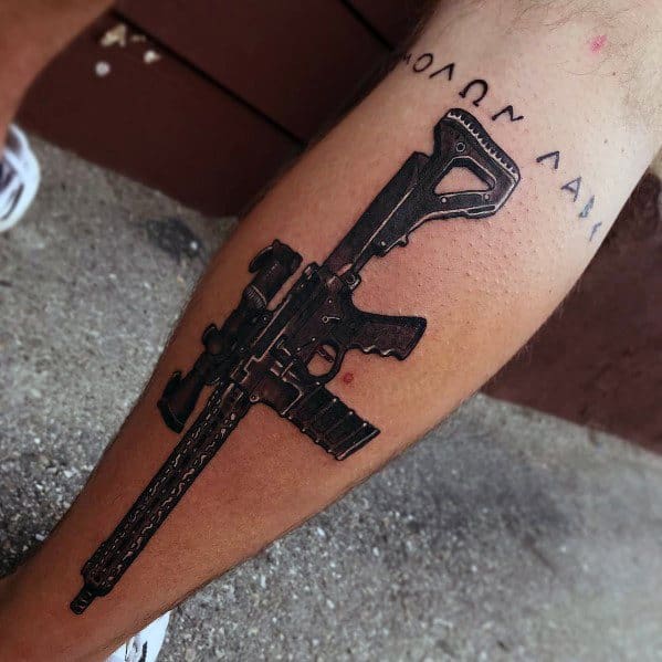Black and grey AR-15 tattoo on the leg with "Molon Labe" text, symbolizing defiance, strength, and the right to bear arms with a bold design.