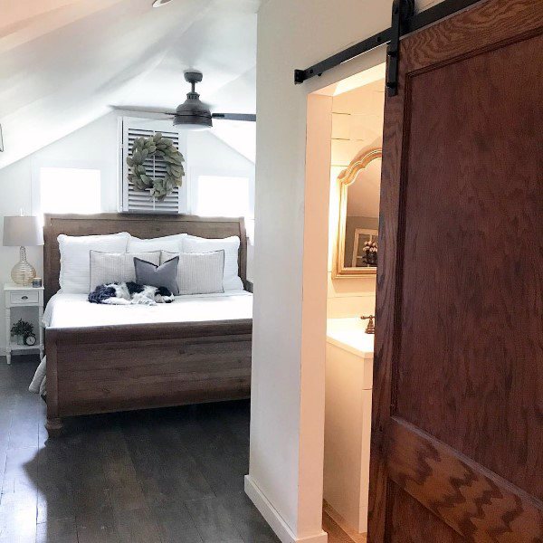 Cozy attic bedroom with a wooden bed, sliding barn door, and a dog resting peacefully