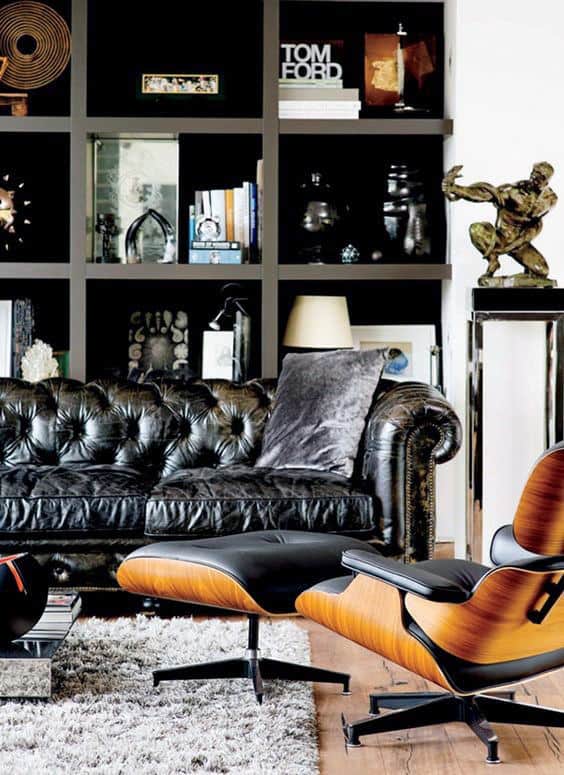 Black leather sofa with modern wood-accented lounge chair in front of a stylish bookshelf.