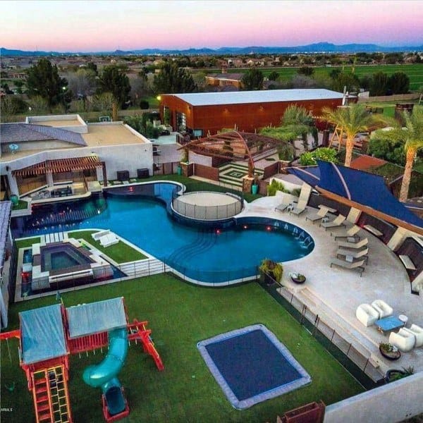 Luxurious backyard with custom pool, trampoline, play area, and modern lounge spaces.