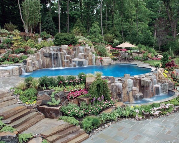 Backyard oasis with cascading waterfalls, natural stone pool, and vibrant garden landscaping.