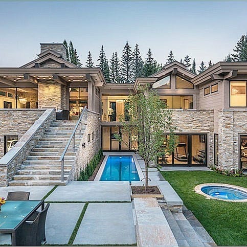 Luxury home with modern pool, hot tub, stone facade, and spacious outdoor living areas.