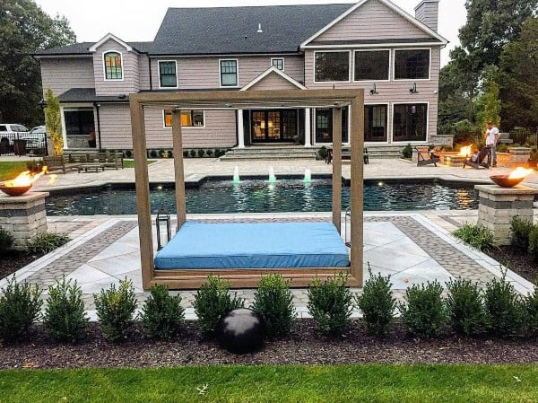 Modern backyard with a pool, fire bowls, a floating daybed, and a luxurious patio design.