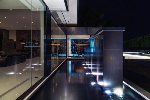 Sleek modern wall fountain with illuminated water feature reflecting a luxurious glass interior.