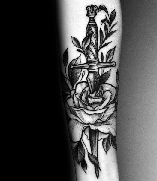 Black and gray tattoo of a dagger through a rose with leaves