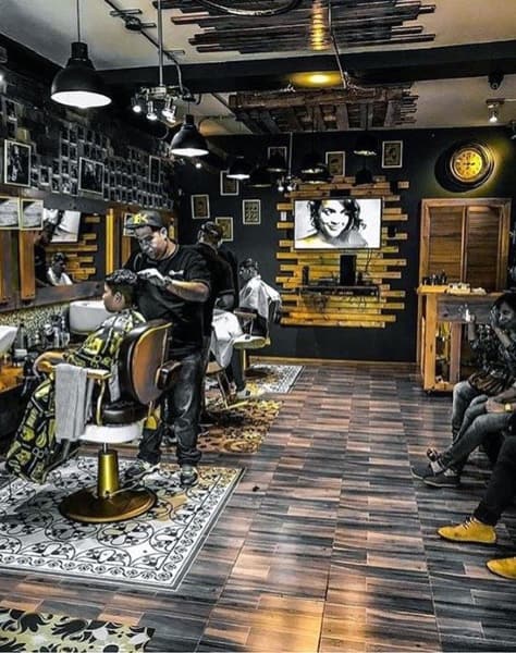 Barber shop with wood accents, patterned flooring, modern chairs, and wall-mounted decor.