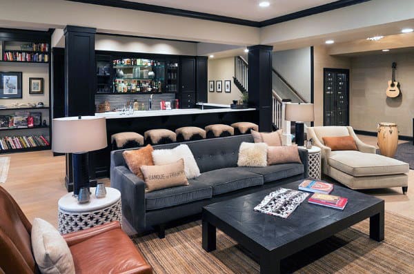 Cozy living area with sofas, a stylish bar, guitar on the wall, bookshelves, and warm lighting