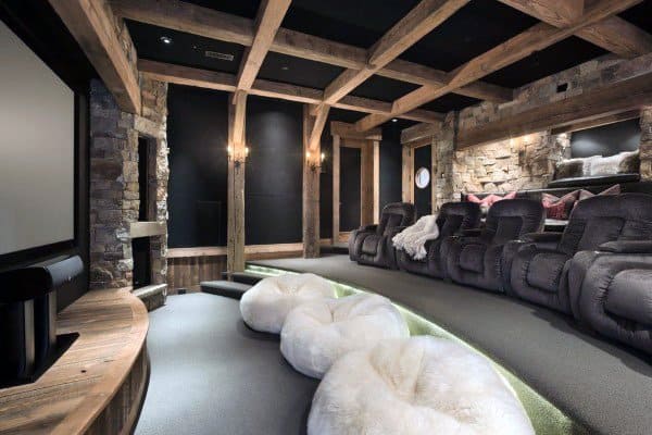 Home theater with exposed wooden beams, stone walls, recliner seating, and cozy bean bag chairs.