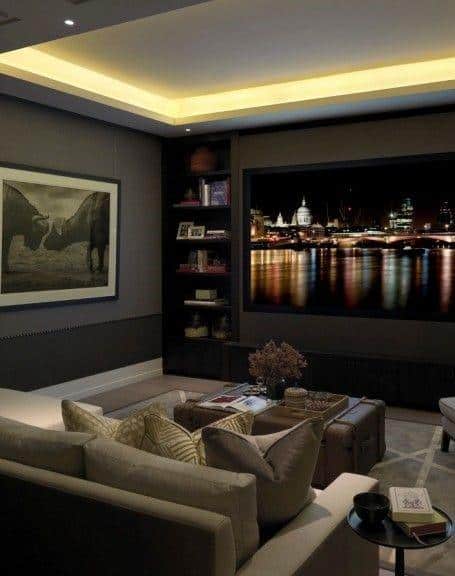Cozy basement home theater with cove ceiling lighting and large screen display.