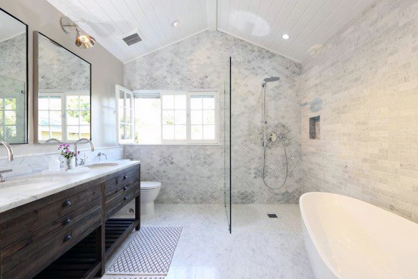 Spacious bathroom with shiplap ceiling, walk-in shower, freestanding tub, and wooden vanity.